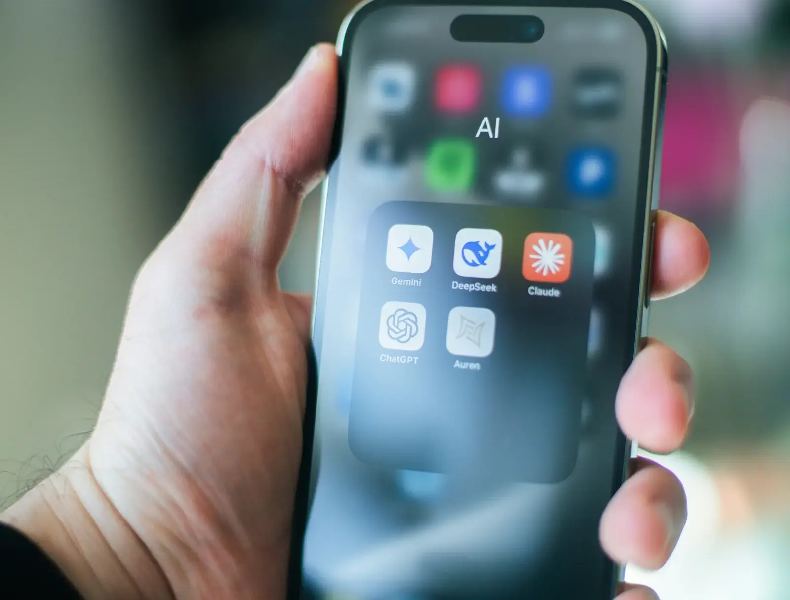 An image of a person holding their phone with various AI tools displayed on the screen